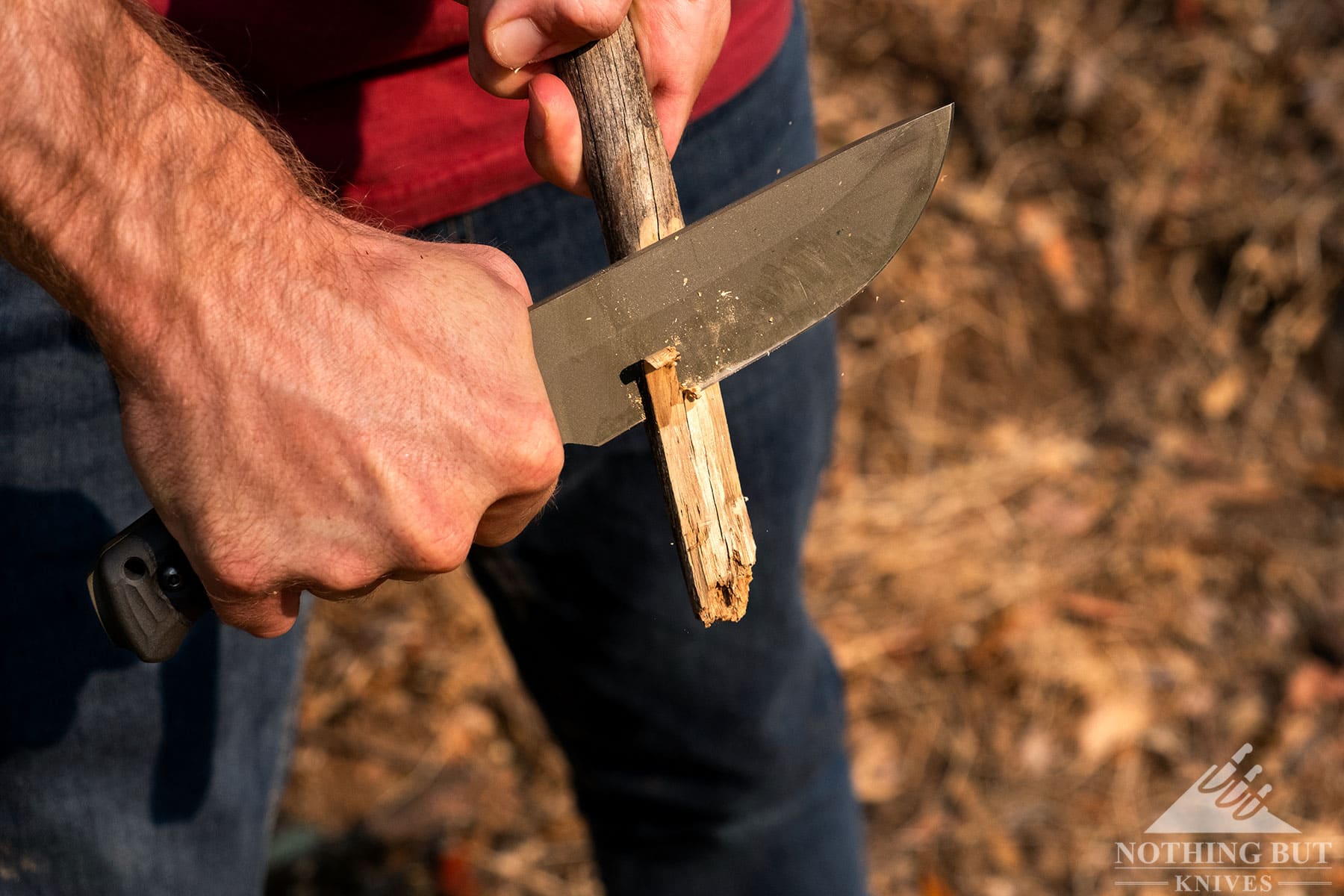 A close-up of the Schwarz Lost Trail 5 camp knife carving a stick. 