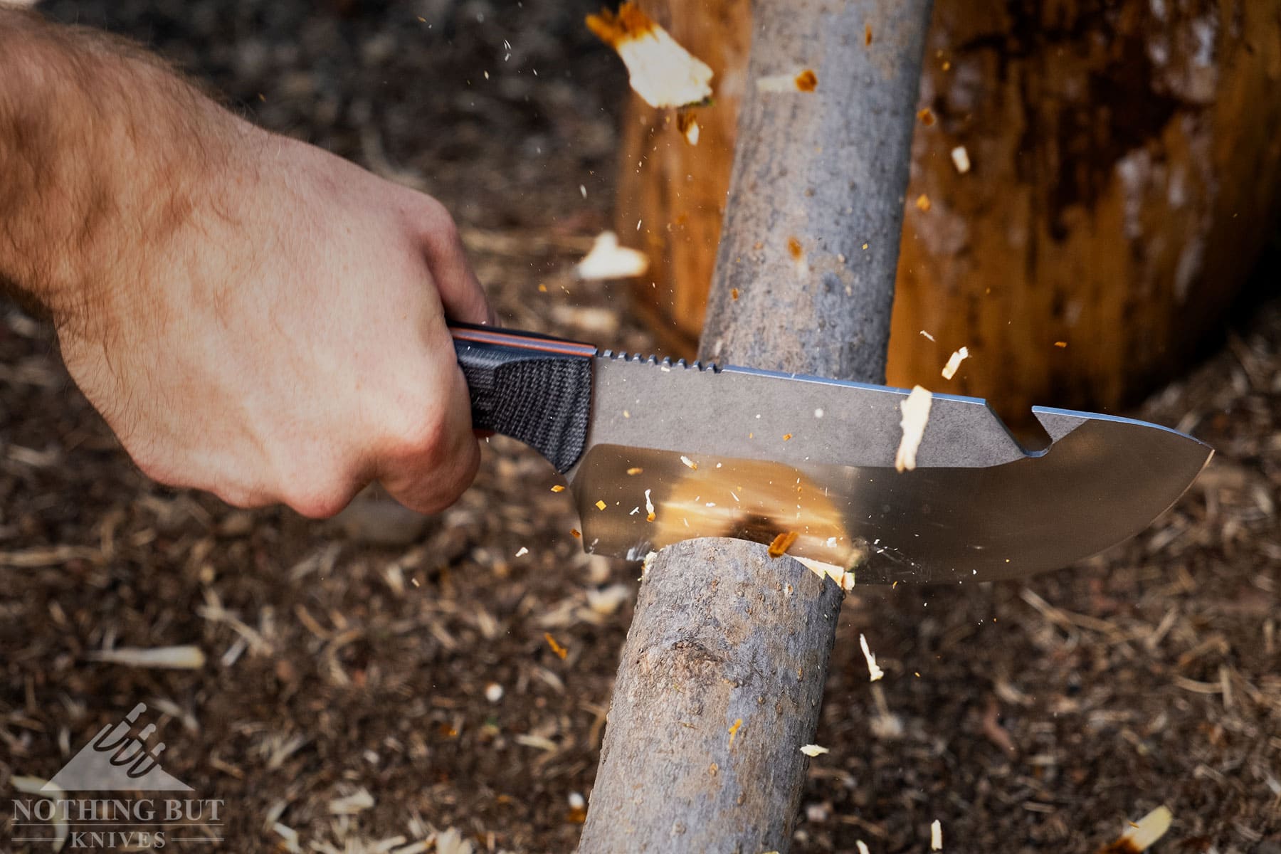 A close-up of the Maxsa bushcraft chef knife being used to chop a small log.