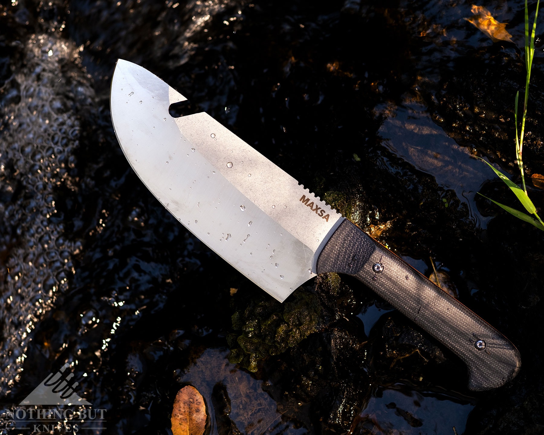 The Maxsa Blade knife on top  of rocks next to a creek. 