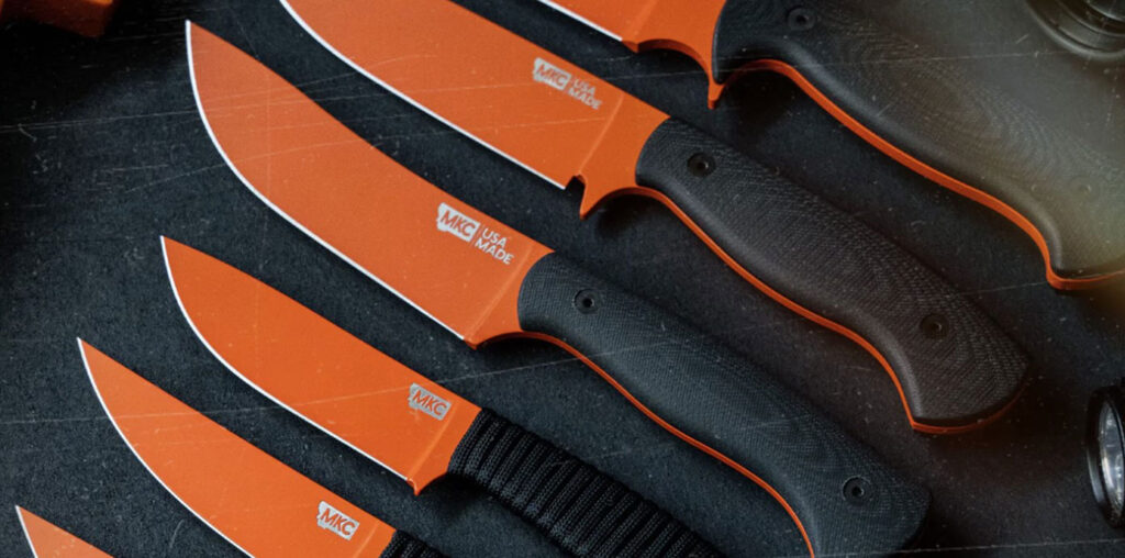 A top-down view of five different Montana Knife Company knives with orange handles on a table. 