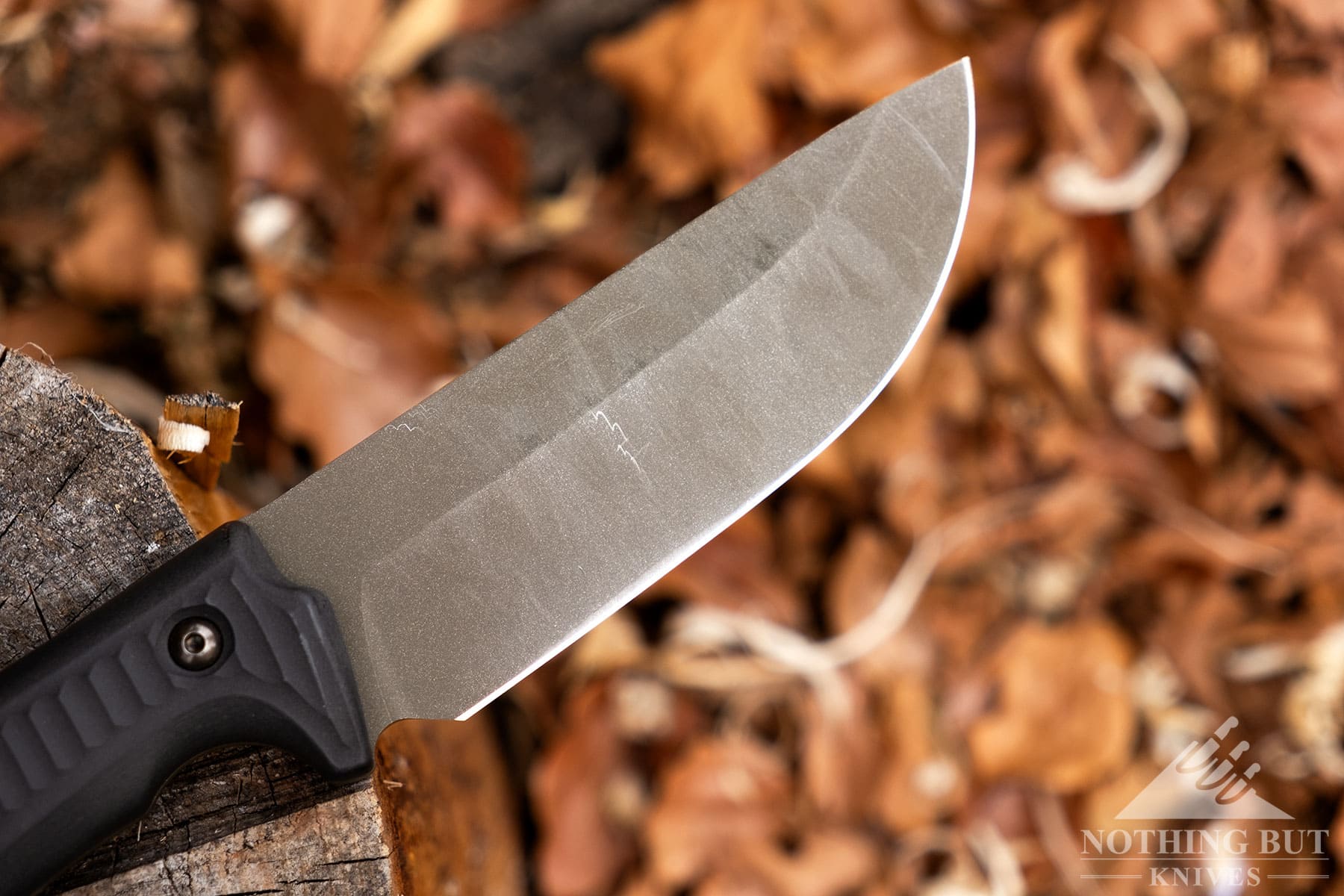 A macro image of the Schwarz Knives Lost Trail 5 OD green blade covered in scrapes and scratches after weeks of use.