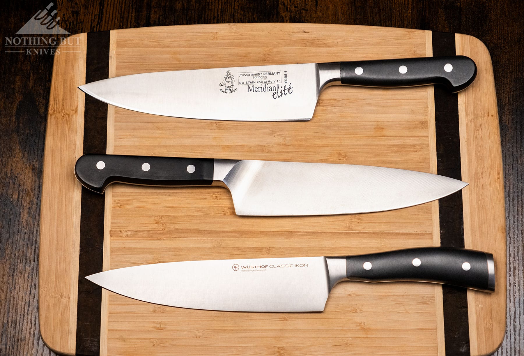 An overhead view of three 8-inch German chef knives on a bamboo cutting board. 