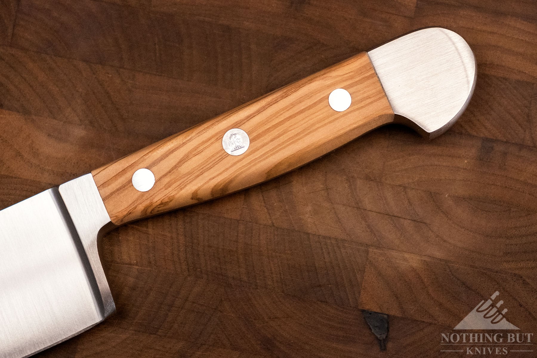 A close-up of the Olve wood handle of a Gude Alpha chef knife.