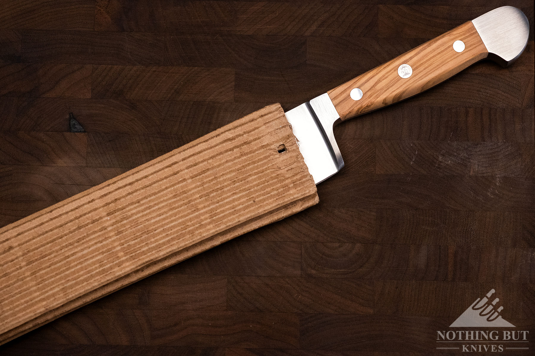 An overhead view of a Gude 8 inch chef knife with its handle sticking out of its minimalist carboard packaging.