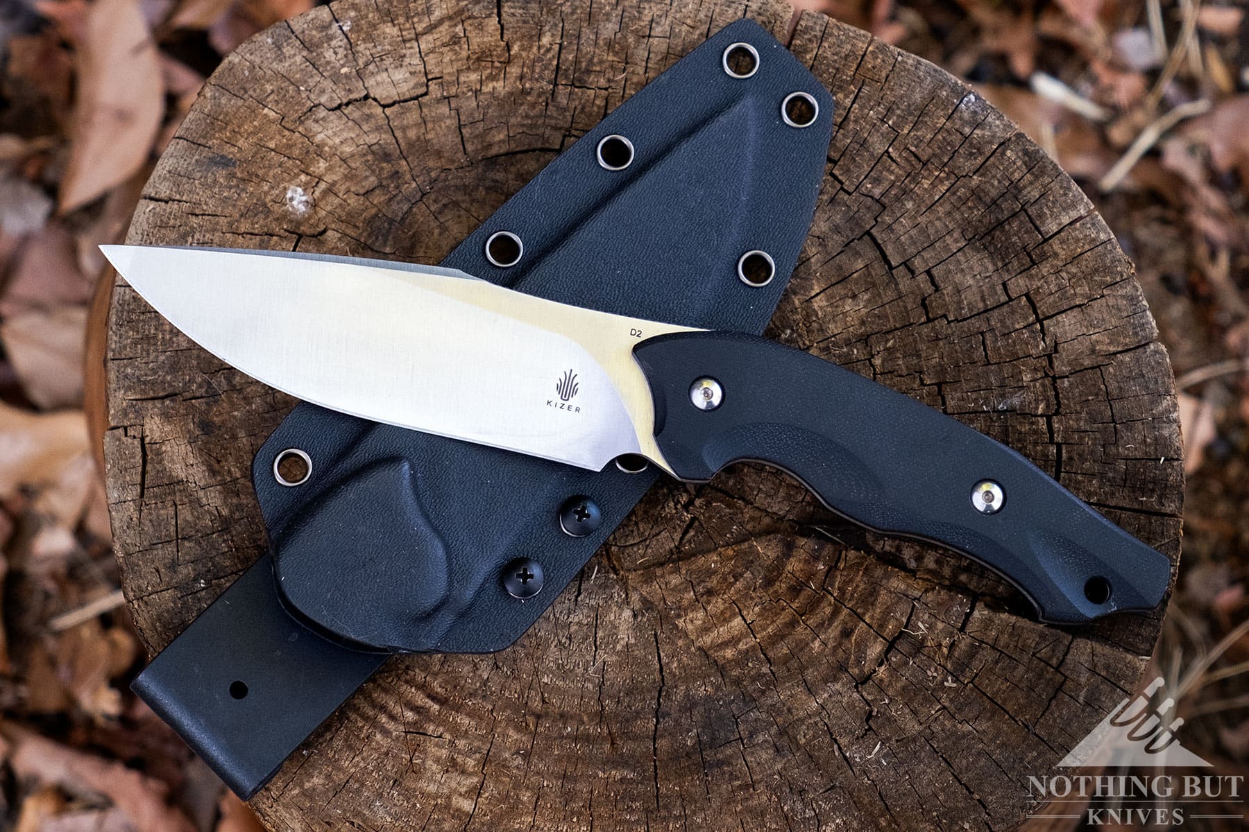 The Kizer Magara fixed blade knife sitting on top of its kydex sheath with a rotating clip. 