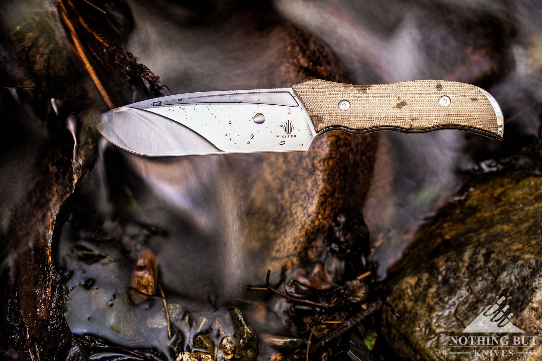 The Kizer Metapropitzal sticking out of a piece of driftwood in a mountain creek.