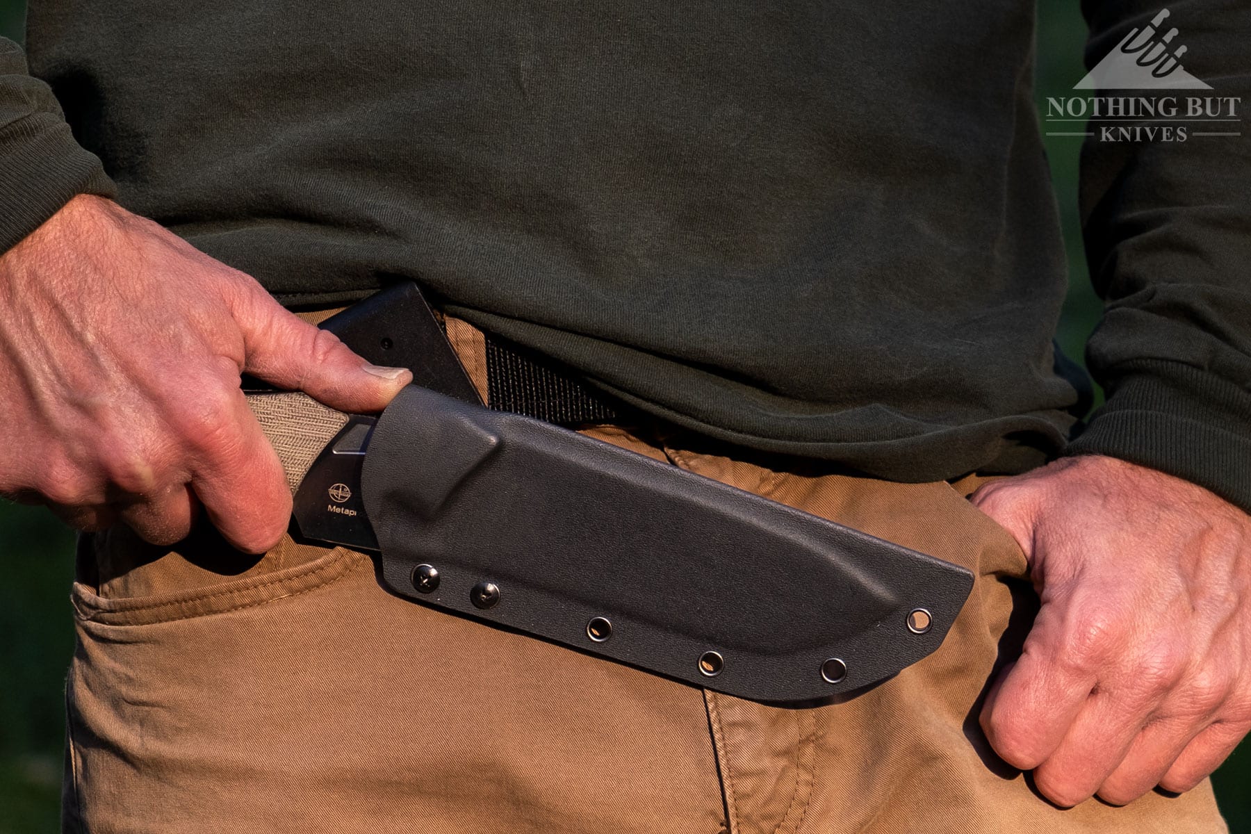 A close-up of the Kizer Metapropitzal fixed blade knife in its sheath on a person's waist. 