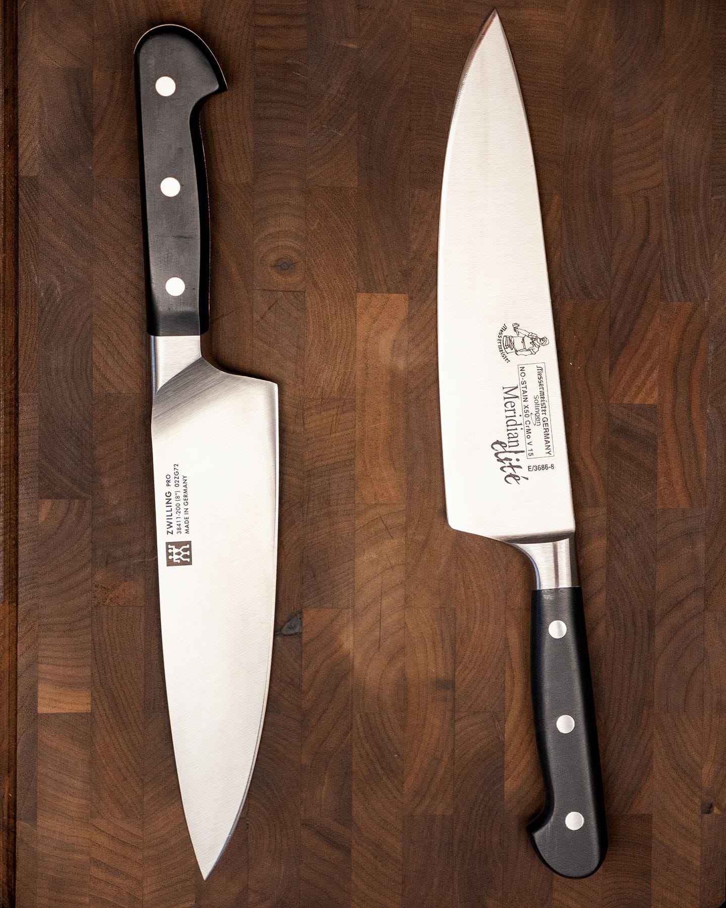 An overhead shot of two German made chef knives on an end grain cutting board.