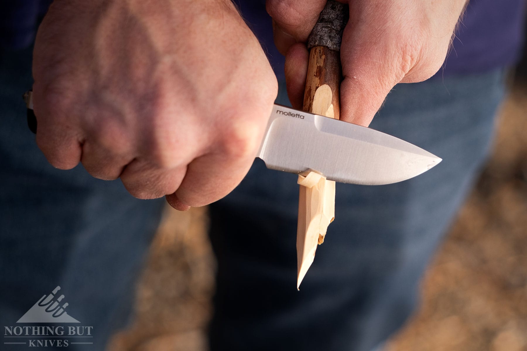 A close-up of the LionSteel SR22 being used to carve a stick. 