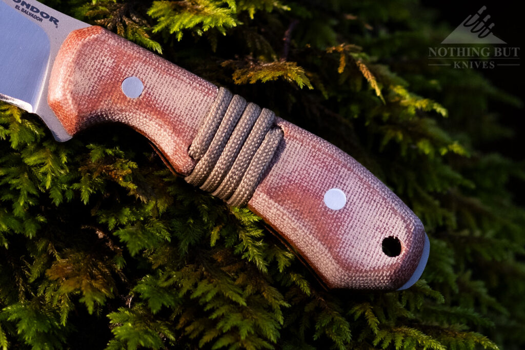 An overhead close-up view of the Mountaineer's canvas Micarta Handle resting on top of a mossy rock. 