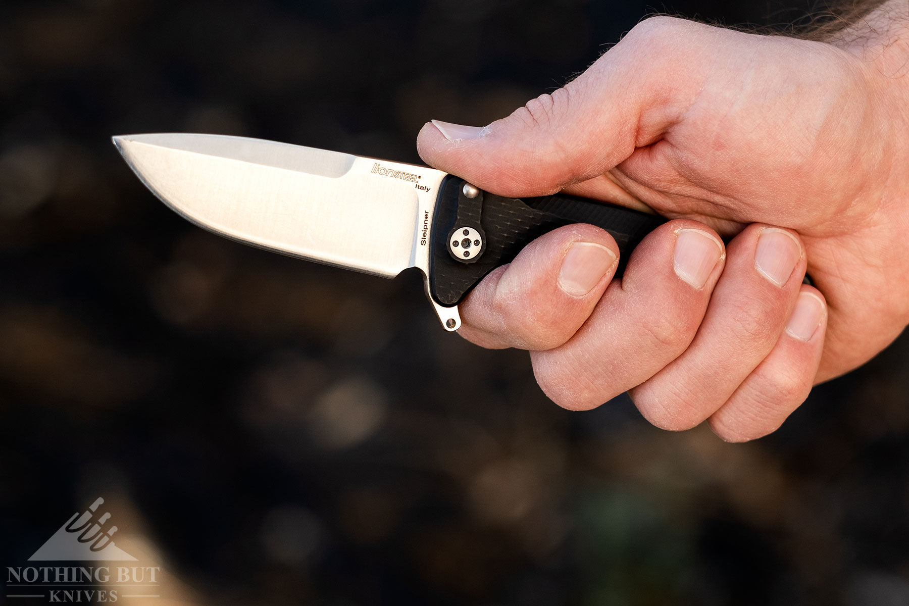 A close-up of a person's right hand gripping the aluminum handle of the LionSteel SR22. 