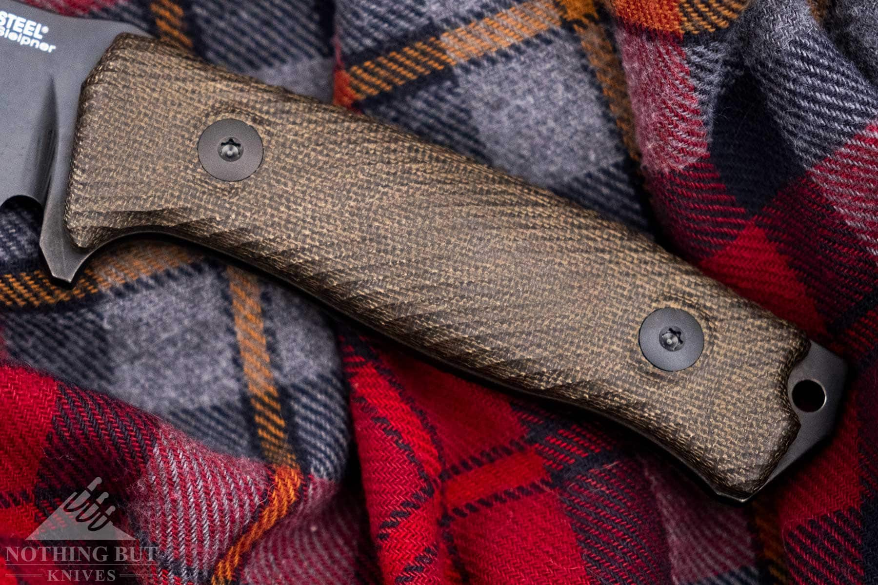 An overhead view of the LionSteel M5 Micarta handle on top of a flannel shirt.