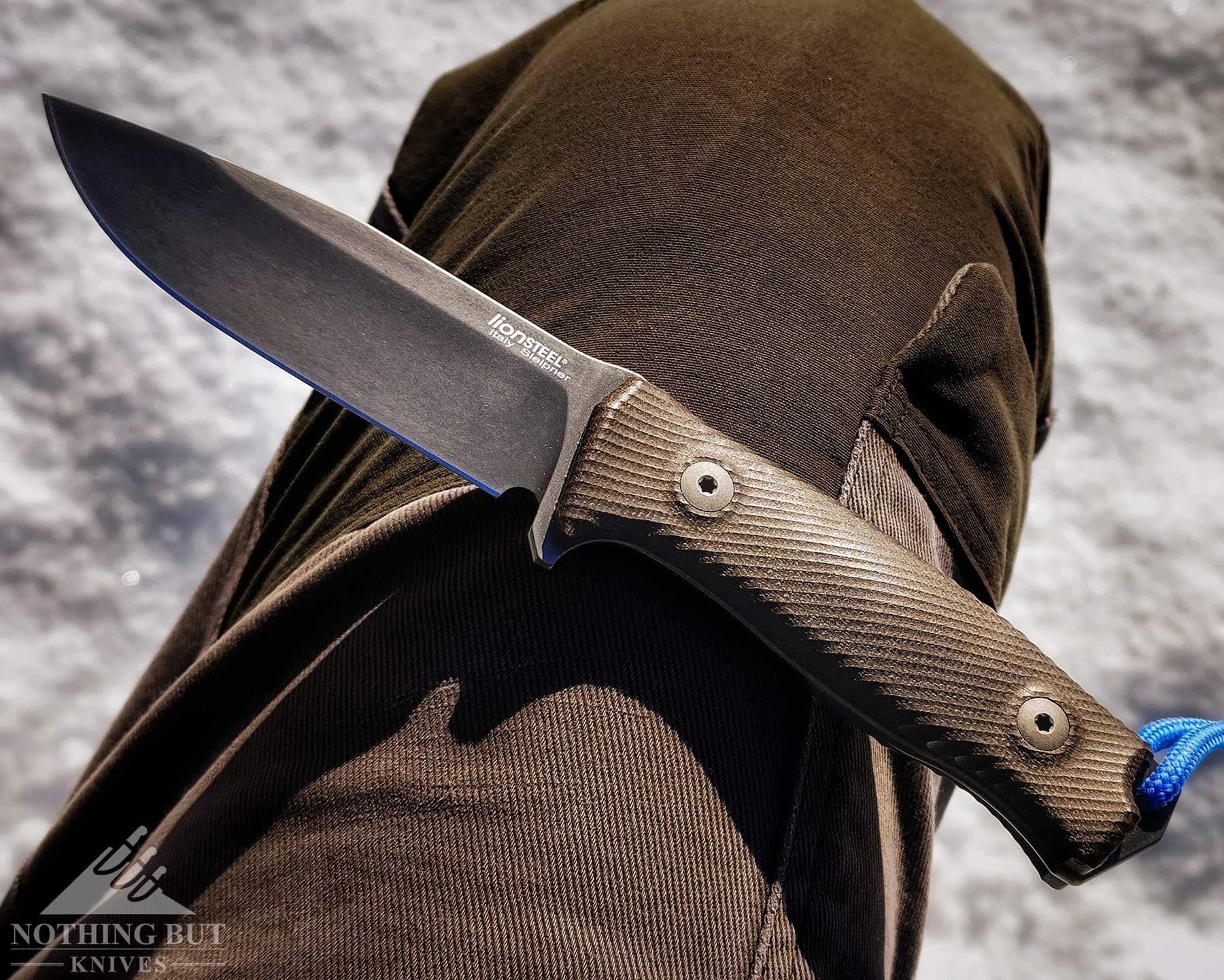 The LionSteel M5 resting on a person's knee above snow covered ground.