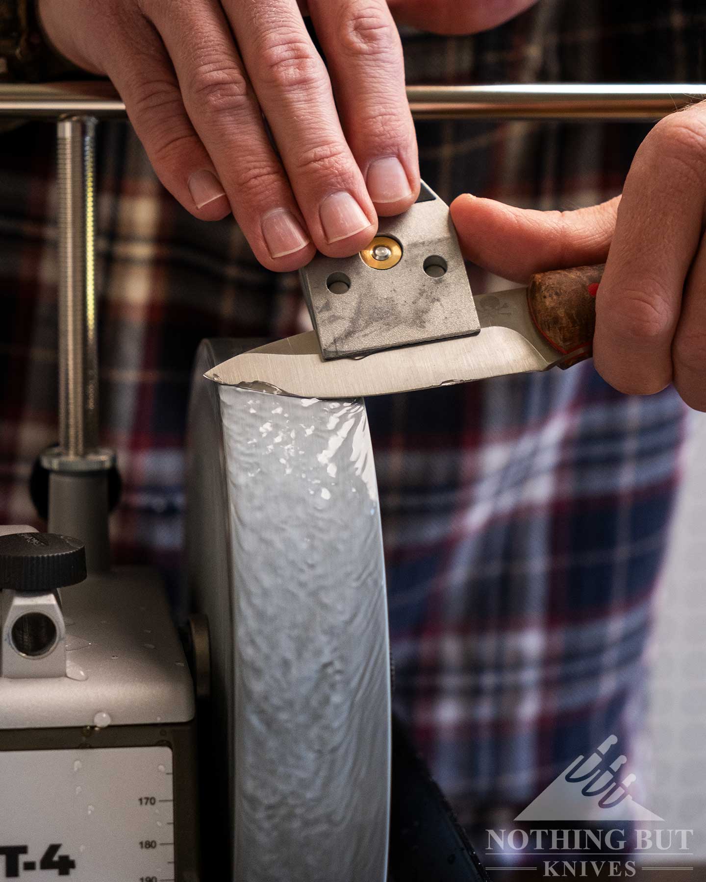 A close-up of a medium sized fixed blade knife being sharpened on the grinding wheel of the Tormek T-4 Bushcraft grinder.