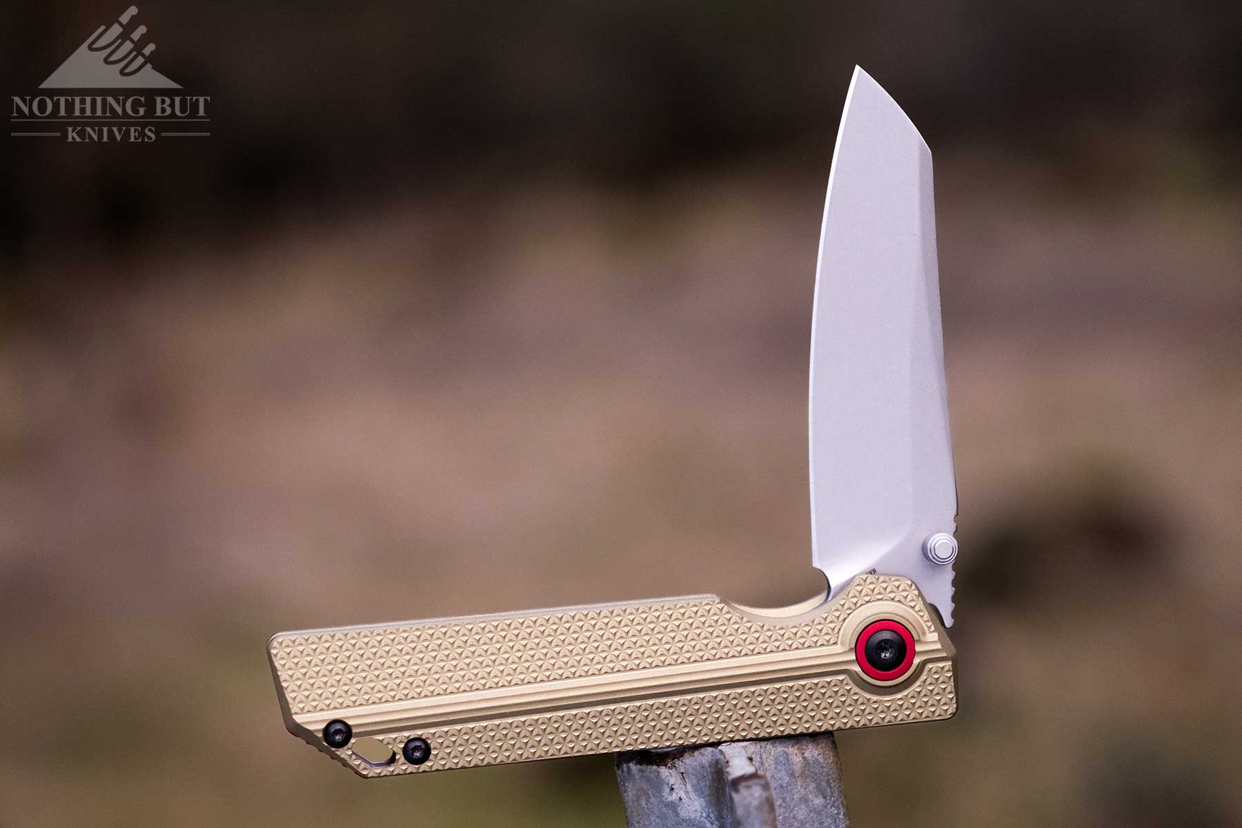 The Ken Onion designed Oknife XEN-OAL folding knife balanced on a steel fence post.