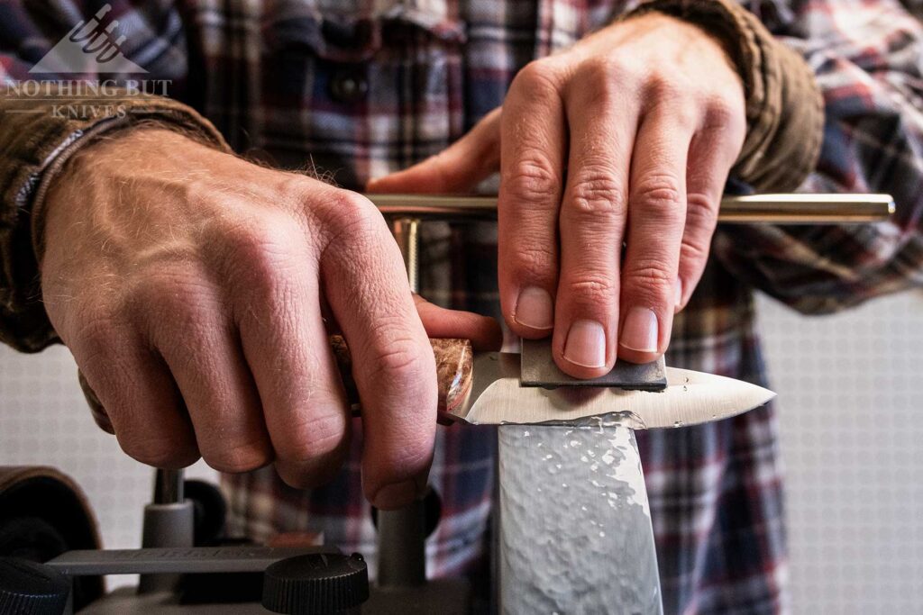 A close-up of an AEB-L steel knife  being sharpened on the Tormek T-4 grinder.