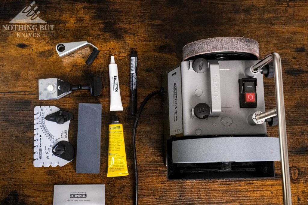 An overhead view of the Tormek T-4 grinder knife sharpener with its included accessories next to it on a tabletop. 