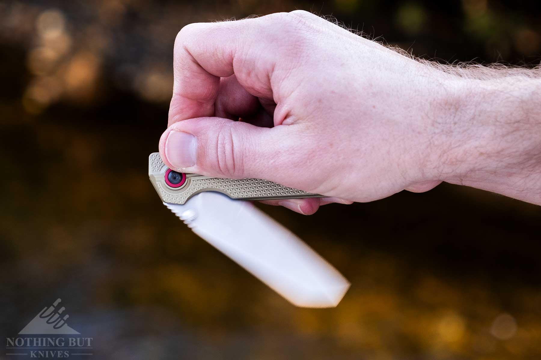 A close-up of the XEN-OAL pocket knife being flipped open outdoors. 